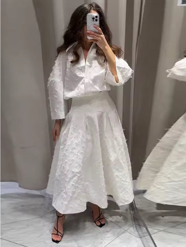 Elegante witte tweedelige set met oversized blouse en geplooide rok